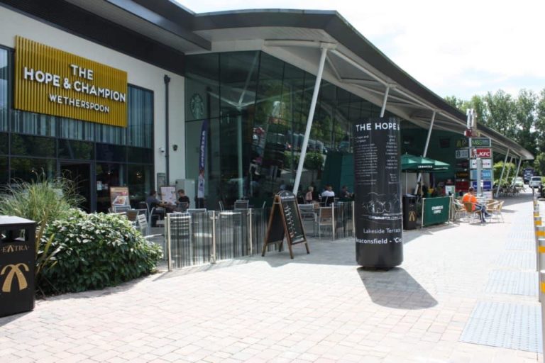 A modern roadside pub with outdoor seating on a sunny day.