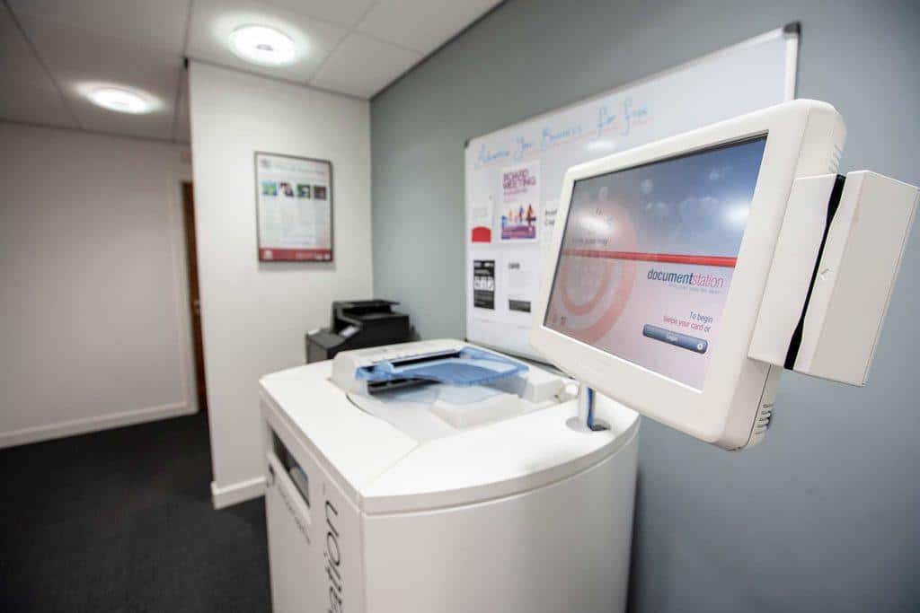 A modern office lobby with an interactive terminal, brochures, and a printer on a sleek white counter.